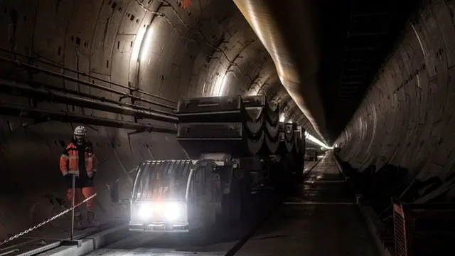 Operário ao lado de maquinário dentro de túnel em construção