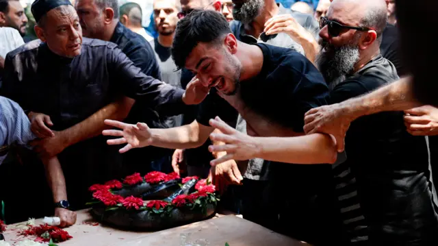 İsrail'in kuzeyinde, Arapların çoğunlukta yaşadığı Tamra kasabasında füze isabet eden bir evde aynı aileden dört kişinin cenazesinde ağlayan dostları ve akrabaları.