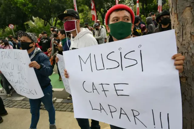 Seorang musisi Indonesia memegang plakat yang bertuliskan "musisi lapar!"
