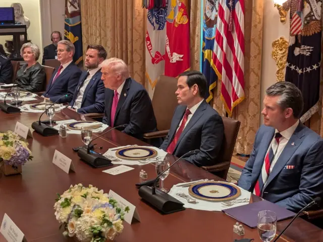 Трамп та інші члени американської делегації сидять за столом