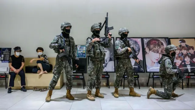 P﻿ara personel militer Korsel sedang menjalani sesi latihan di sebuah pusat perbelanjaan di Seoul, Agustus lalu. Poster para bintang K-Pop tampak di latar belakang.