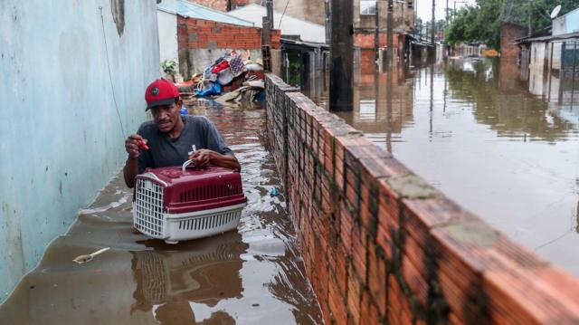 Homem atravessando águas inundadas