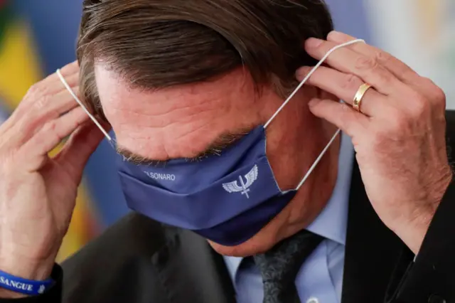 Bolsonaro se atrapalha ao vestir máscara hospitalar