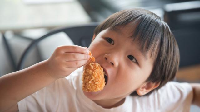 niño comiendo alitas de pollo