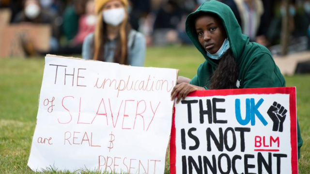 A young black girl holds placards related to the UK's slavery past in a protest in the city of Bristol