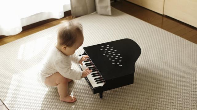 Bebê mexe em um piano de brinquedo