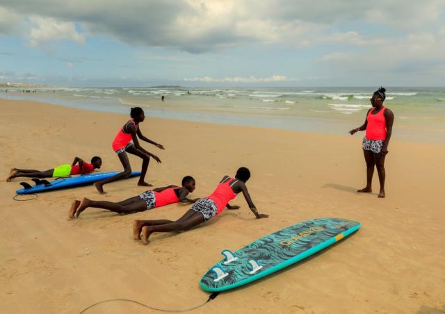Khadjou Sambe enseigne aux filles et aux femmes les techniques de surf sur la plage