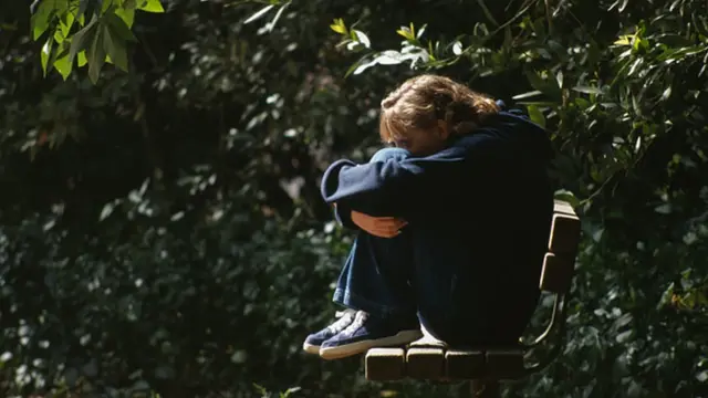 Devojčica usamljeno sedi na klupi