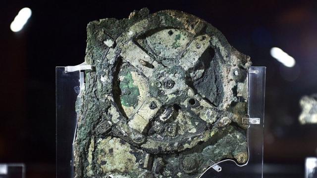 L'image montre un morceau du mécanisme d'Antikythera au musée en Grèce.