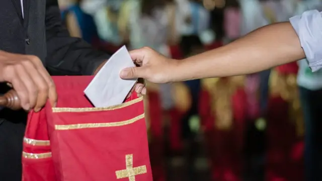 Pessoa colocando doação no sacosport betboooferendas para a igreja