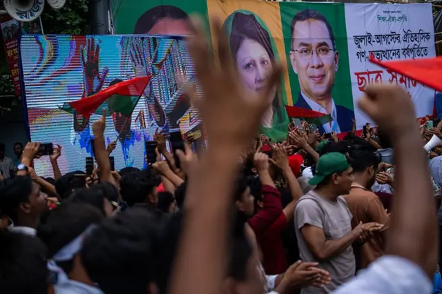 খালেদা জিয়া ও তারেক রহমানের ছবিসহ একটি ব্যানার, সামনে হাততালি দিচ্ছে অনেক মানুষ