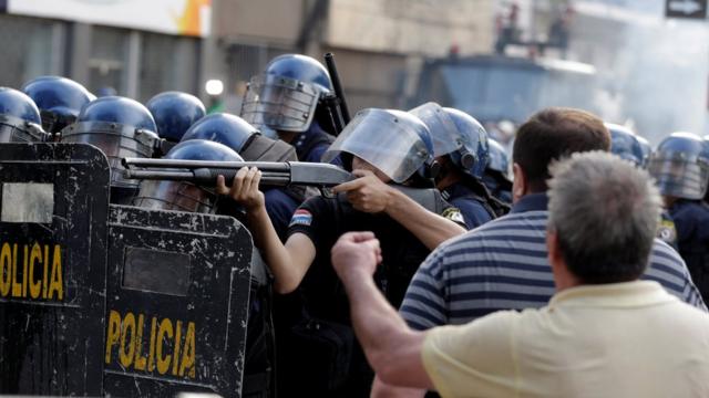 Un policía apuntando un fusil durante las protestas en Paraguay por el proyecto de reelección presidencial.