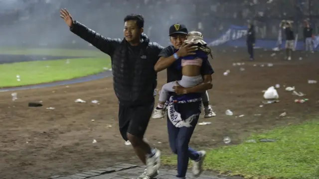 Hombre carga a un bebe en el partido.