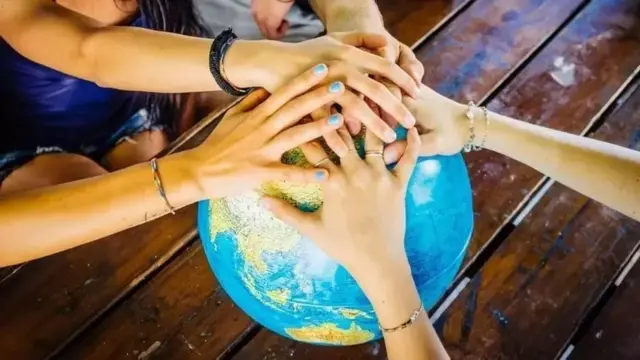 มือคนหลายคนจับลูกโลก