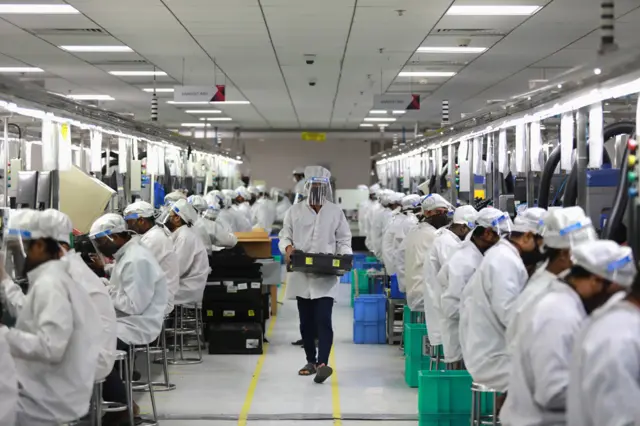Hindistan'da fabrikaların tekrar açılmasıyla birlikte cep telefonu üretimi kaldığı yerden devam ediyor. Fakat yeni düzende işçilerin tamamı koruyucu ekipman giyiyor