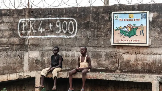 Deux jeunes garçons assis devant devant un mur au sud de la ville de Bangui.