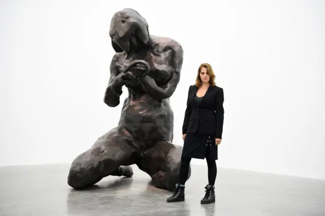 Artist Tracey Emin standing next to a large bronze sculpture of a female figure