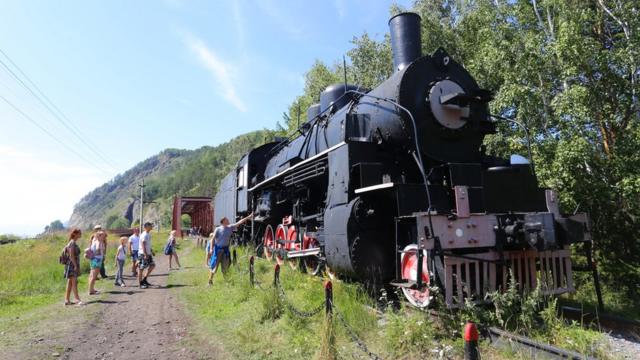 游客在贝加尔湖畔观赏一台西伯利亚铁路的老蒸汽机车