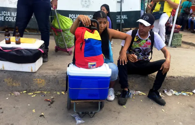 Personas sentadas en el cruce fronterizo