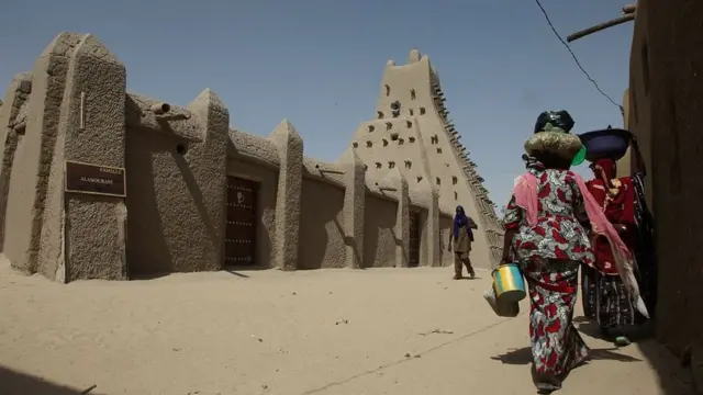 Des ouvriers posent le 19 septembre 2016 devant les portes d'une mosquée vénérée du 15e siècle qui ont été découpées à la hache par des djihadistes dans l'ancienne ville de Tombouctou au Mali en 2012, et qui sont maintenant dévoilées restaurées dans leur gloire d'antan.