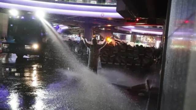 Thai police officers look down at a road block at an intersection near a pro-democracy protest in Bangkok, Thailand, 16 October 2020.