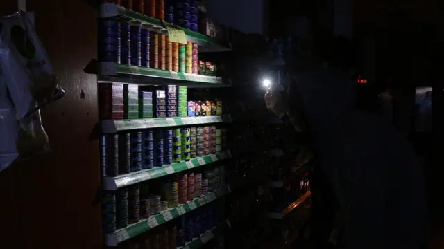Warga menggunakan cahaya dari telepon genggam mereka untuk menyoroti deretan barang dagangan di supermarket di Buenor Aires, Argentina, saat listrik padam