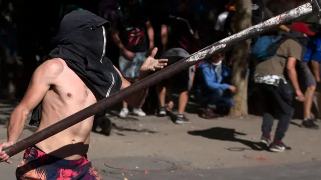 Hombre con torso desnudo carga con una barra de metal.