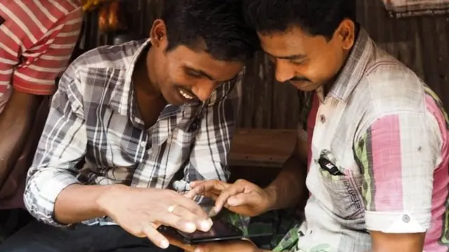 मोबाइल फोन देखते दो व्यक्ति