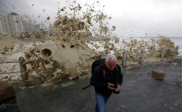 A man runs from sea spray as storms hit Cape Town, South Africa, June 7, 2017.