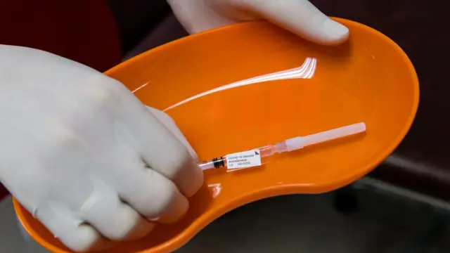 Лоток со шприцем в руках медсестры.