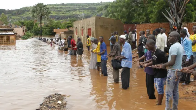 People dey hold rope for inside flood water