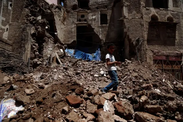 طفل يمشي على أنقاض مبنى تاريخي بعد أن انهار جزئيا بسبب الأمطار الغزيرة في مدينة صنعاء القديمة، 13 أغسطس/آب 2020