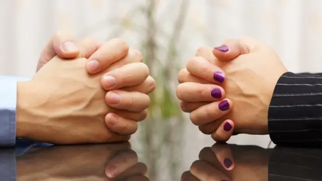 Man and woman at table with hands clasped