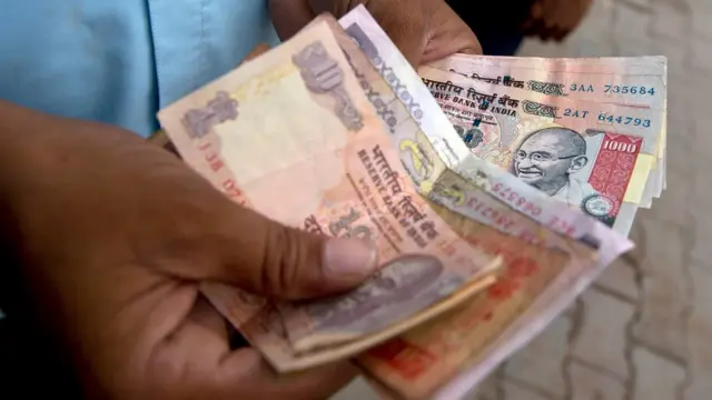 રૂપિયાની નોટ ગણતા વ્યક્તિની તસવીર