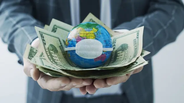 Un globo terráqueo con una mascarilla sobre billetes de dólares