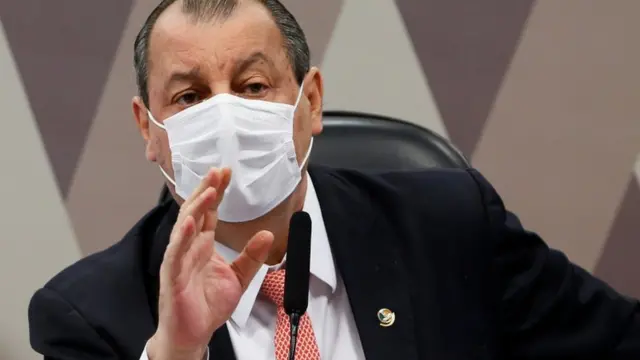 De máscara e sentado, Aziz gesticula na CPI
