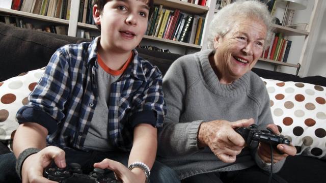 бабушка с внуком играют на игровой приставке