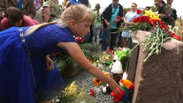People lay flowers at the monument to the victims of the Malaysia Airlines flight MH17 crash, in the village of Grabovo, Ukraine, 17 July 2017