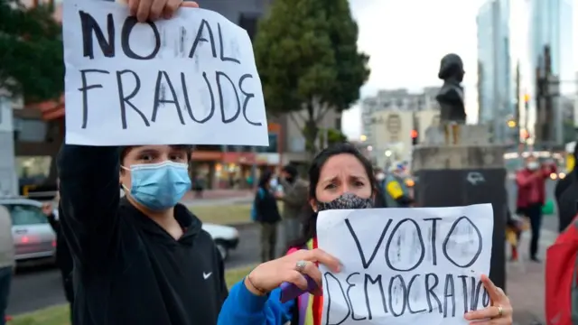 Dos seguidores de Yaku Pérez con carteles en contra del fraude.