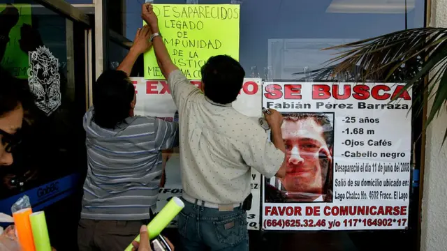 Personas colocan letreros de desaparecidos.