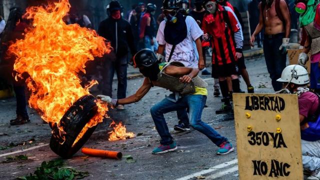 Protestantes venezolanos prenden fuego un neumático.