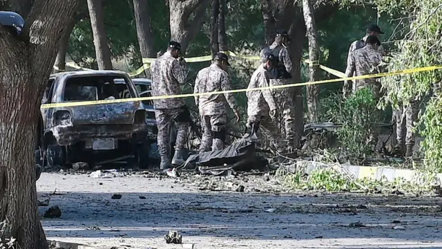 Pakistan security personnel comb the area around the wreckage of a vehicle destroyed by a suicide bomb on 6 October