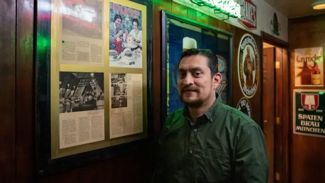 Sergio Vázquez posa al lado de recortes de un artículo sobre su bar cuando todavía era una cafetería en los años 70.