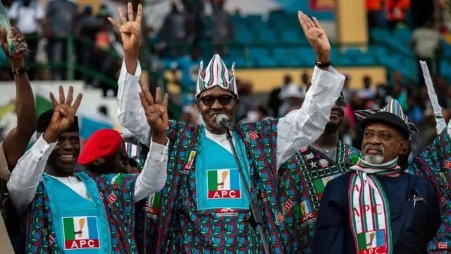 Le président nigérian Muhammadu Buhari et un membre du parti au pouvoir All Progressive Congress (APC) saluent la foule de partisans de l'APC à son arrivée pour un rassemblement de campagne politique au stade Teslim Balogun à Lagos le 9 février 2019
