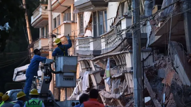 Trabajadores frente a un edificio destruido.
