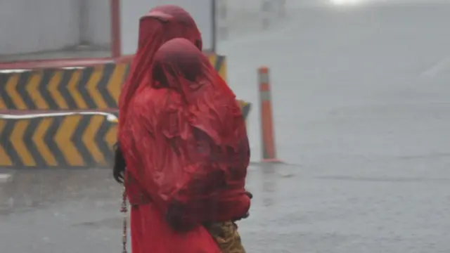 बारिश में भीगती महिला और एक बच्चा