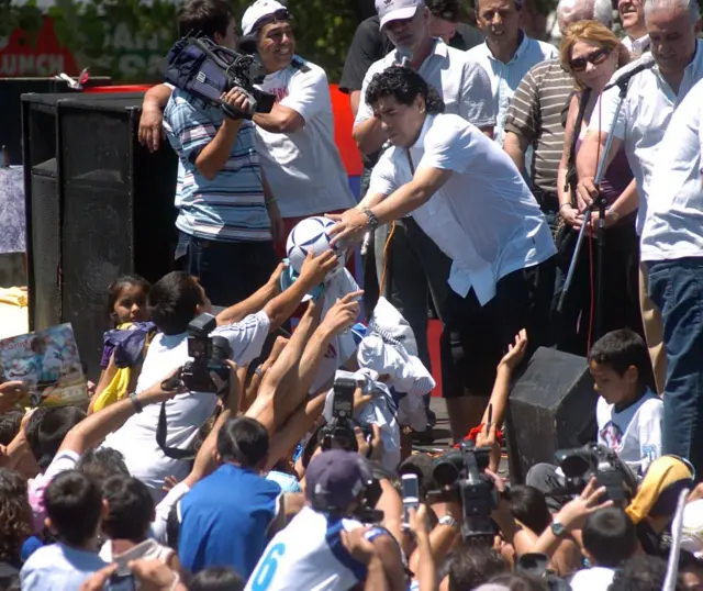Maradona, 2008 yılında doğup büyüdüğü Villa Fiorito'da çocuklara futbol topu imzaladı.