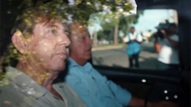 Brazilian spiritual healer Joao Teixeira de Faria, known as "John of God", arrives at a the police station a day after being officially ruled a fugitive