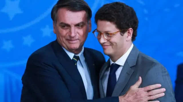 O presidente Jair Bolsonaro sorri e abraça o ministro do Meio Ambiente Ricardo Salles