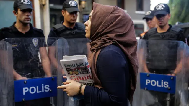 Polis barikatı önünde Özgür Gündem gazetesini taşıyan bir okur